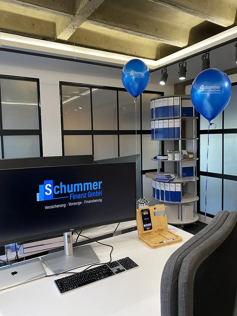 Arbeitsplatz mit Schummer-Finanz-Logo auf dem Monitor